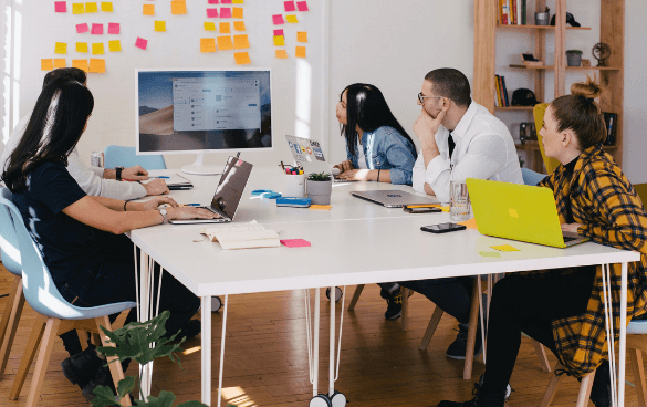 People sitting around an office table looking at a computer