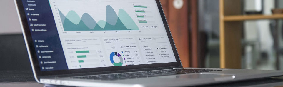 Laptop on a desk displaying analytics data with charts and graphs on the screen.