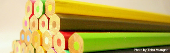 Close-up of a stack of colored pencils with sharpened tips facing forward, displaying a variety of colored leads.