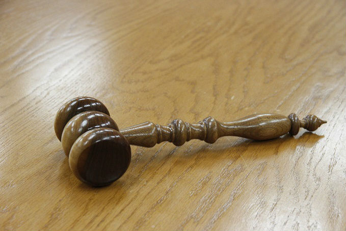 A wooden gavel on a wooden surface.