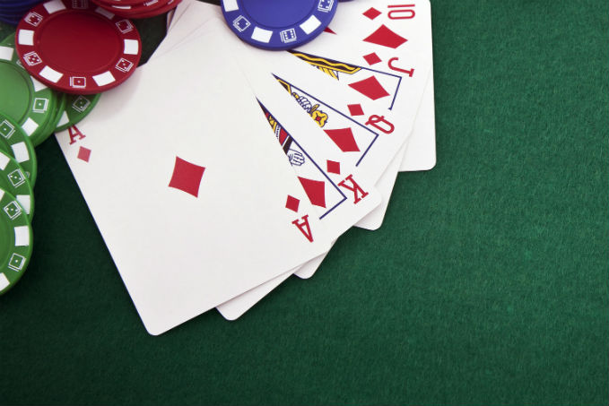 A royal flush in diamonds poker hand on a green felt surface with red, green, and blue poker chips.