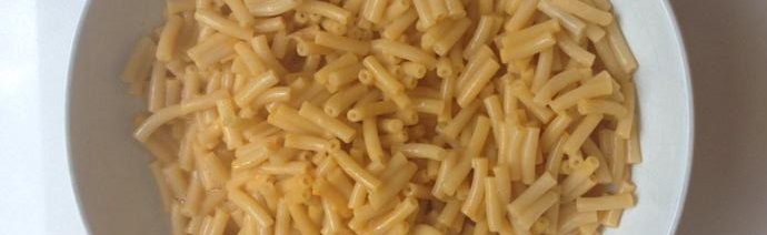 A bowl of plain cooked macaroni pasta on a light surface.