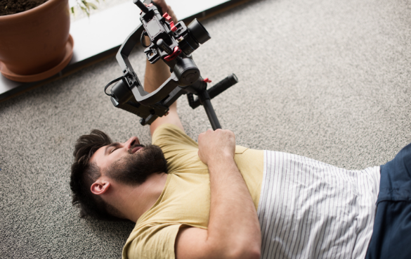 A man holds a camera while lying on the ground