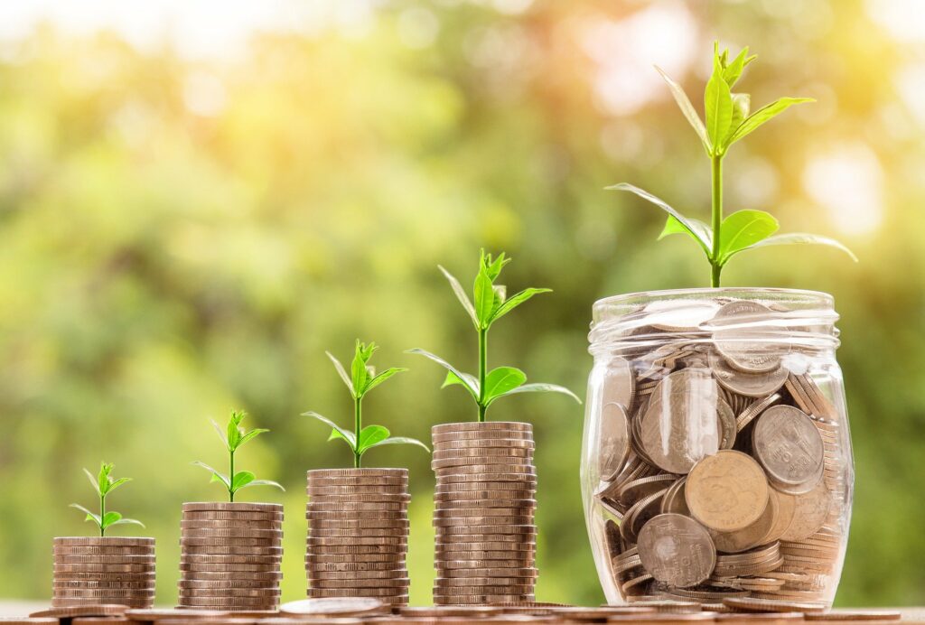 stacks of coins and a jar of coins with plants growing out of them