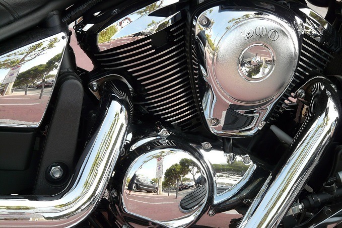 Close-up of a motorcycle engine with cooling fins and chrome accents, featuring a '900' emblem, with reflections of the surroundings on the chrome surfaces.