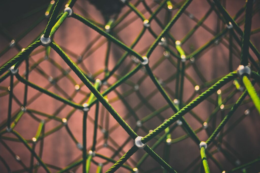 Close-up of a green rope net with white connectors against a softly blurred warm-toned background.