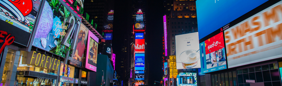 A bustling urban scene at night with illuminated billboards and digital advertisements, reminiscent of Times Square in New York City.