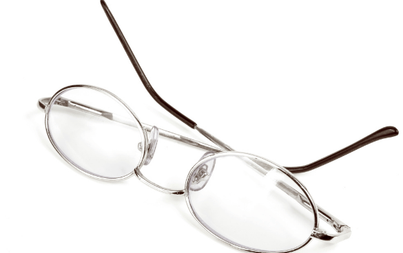 Round silver-framed eyeglasses with thin brown temples on a white surface.