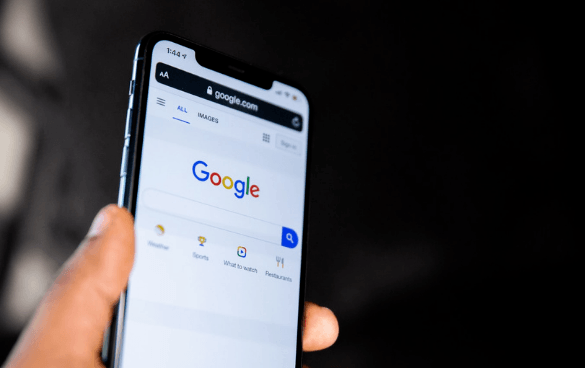 A person holding a smartphone displaying the Google search homepage with options for different search categories.