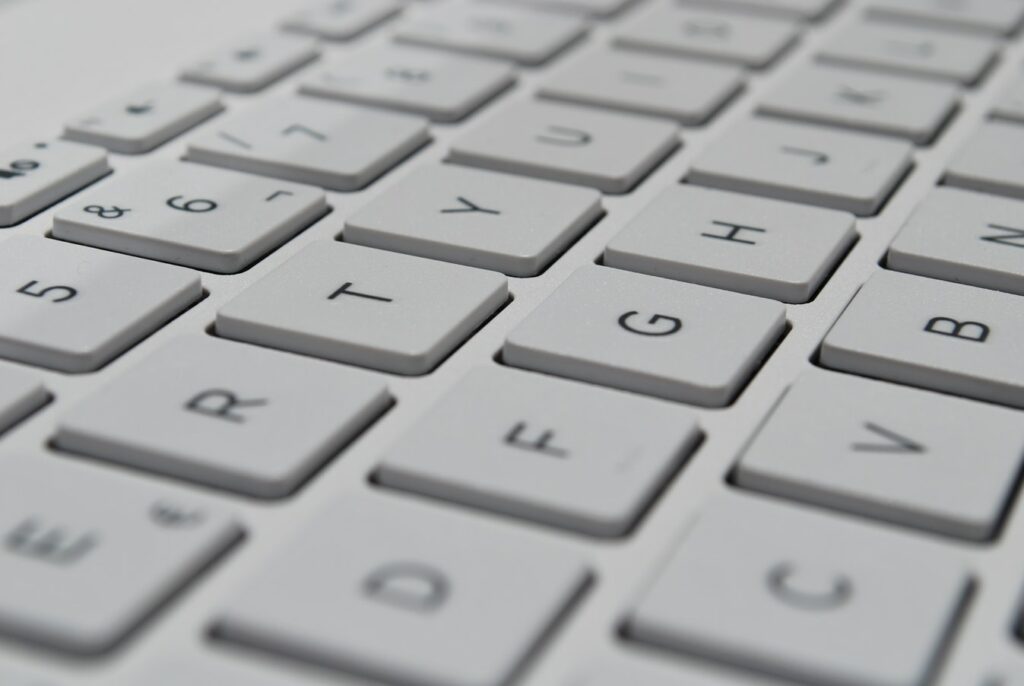 Close-up of a modern computer keyboard with white keys, focusing on the central QWERTY layout with numbers 5 to 0 and letters T to B in sharp focus.