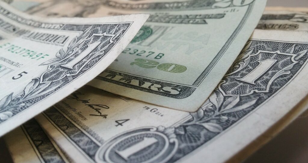 Close-up of several fanned out US one-dollar bills, highlighting the detailed designs and serial numbers.