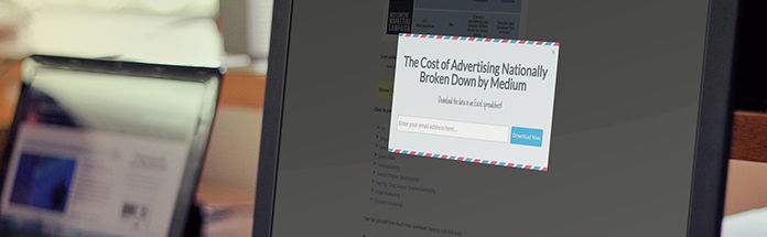 A computer monitor displaying a webpage with a pop-up titled 'The Cost of Advertising Nationally Broken Down by Medium' with a download button and terms and conditions checkbox, on a desk with blurred office items in the background.