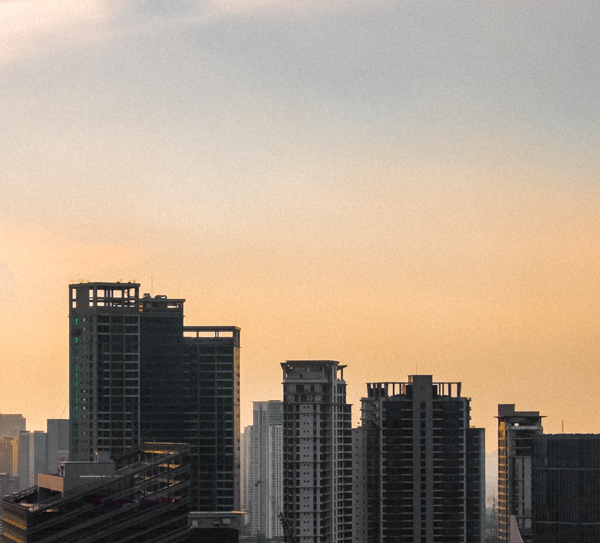 Cityscape with high-rise buildings at sunrise or sunset with a gradient sky from orange to light blue.