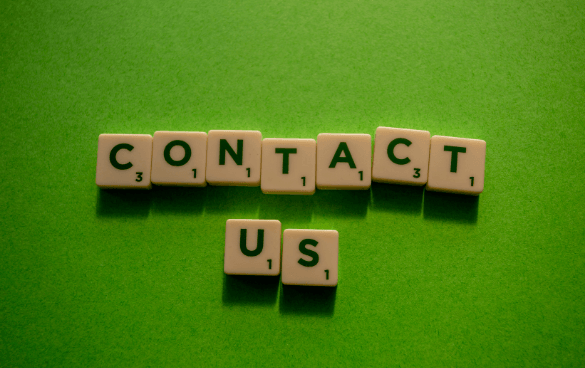 Scrabble tiles spelling out 'CONTACT US' on a green background.