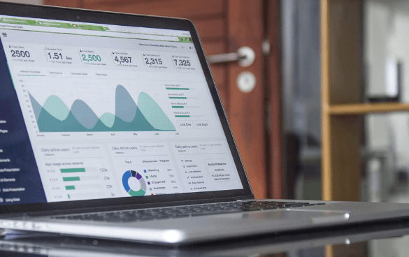 Laptop on a desk displaying a business analytics dashboard with graphs and metrics.