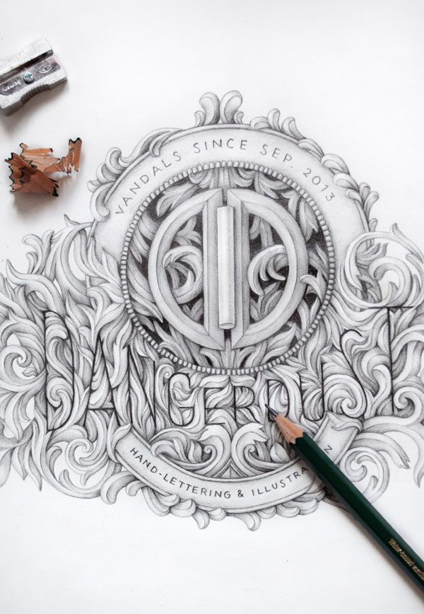 Detailed pencil drawing of an ornate emblem with intertwined letters 'V' and 'S', surrounded by swirls and flourishes, with the text 'VANDALS SINCE SEP 2013' and 'HAND LETTERING & ILLUSTRATION'. A pencil and shavings are also visible on the drawing surface.