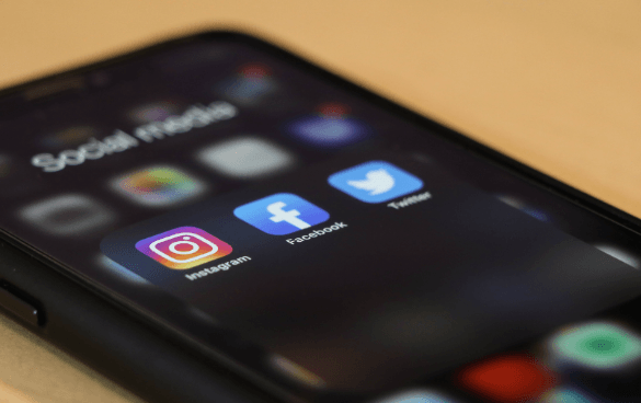 Close-up of a smartphone screen displaying social media app icons for Instagram, Facebook, and Twitter.