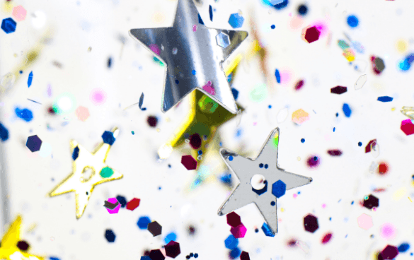 Colorful star-shaped confetti suspended in the air with a bright white background.