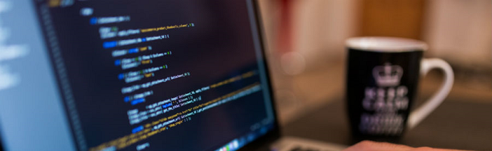 Close-up of a laptop screen displaying code with a blurred coffee mug in the background.