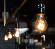 Illuminated light bulb in focus with other bulbs in the background in a dimly lit indoor setting.