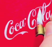 A hand painting the Coca-Cola logo in white on a red background.