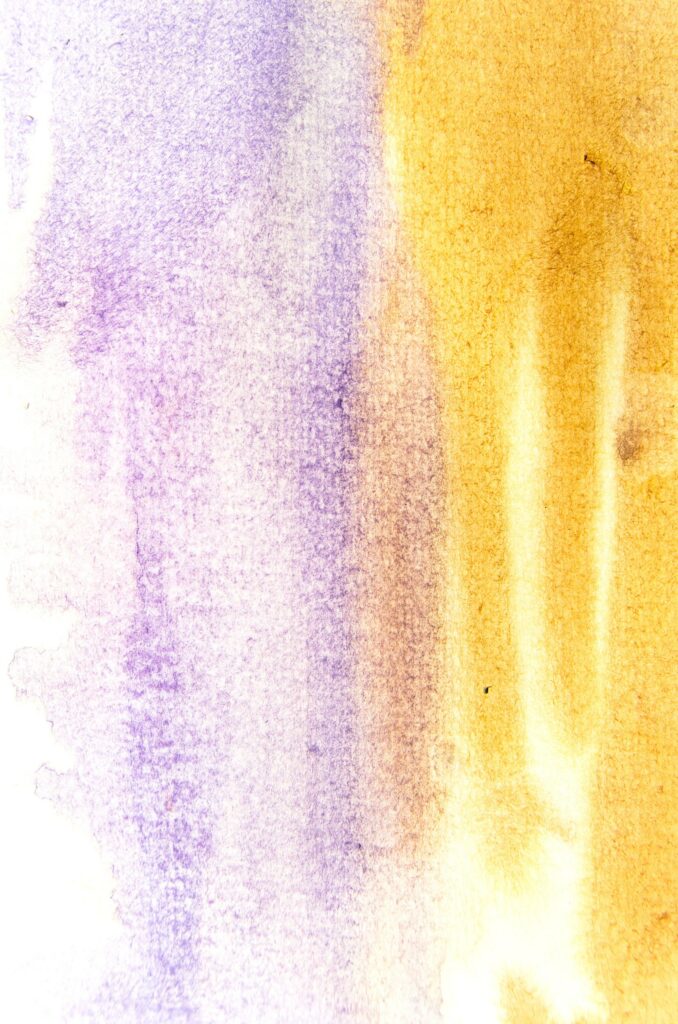 Abstract watercolor gradient transitioning from purple to golden yellow with a soft, textured blend.