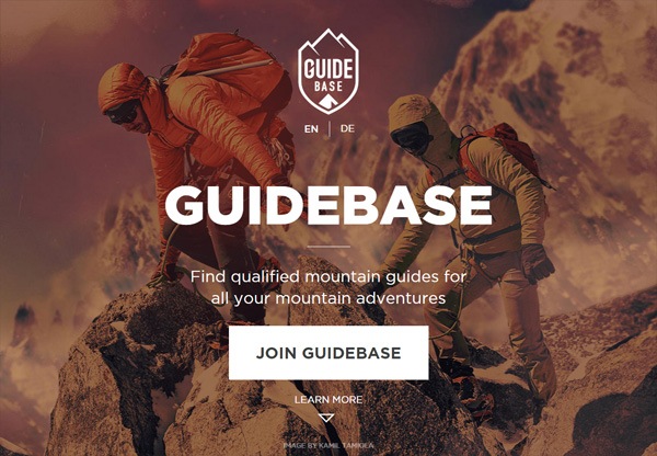 Two climbers ascending a mountain with snow-covered peaks in the background, overlaid with the 'GUIDEBASE' logo, a tagline about finding qualified mountain guides, and buttons to join or learn more about the service, with language options in English and German.