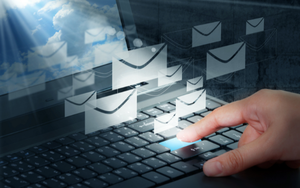 A person's hand interacting with a laptop keyboard, with envelope icons floating from the screen into a cloudy sky, symbolizing email communication.