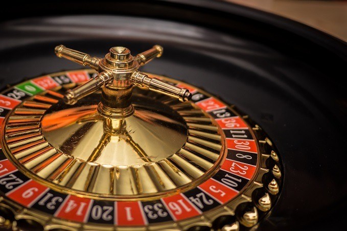 Close-up of a stationary roulette wheel with alternating red and black numbered spaces and a single green zero.