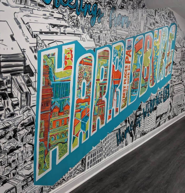 A mural with the word 'LOVE' in large letters filled with colorful illustrations of urban buildings, set against a detailed black and white cityscape background.