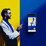 A doctor in a white coat uses a phone, standing by a yellow and blue split wall with a large phone screen displayed.