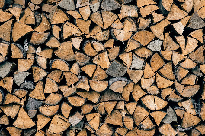 A neatly stacked pile of cut firewood with visible wood grain and varying shades of brown.