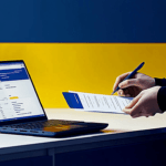 Technician filling out paperwork next to a laptop