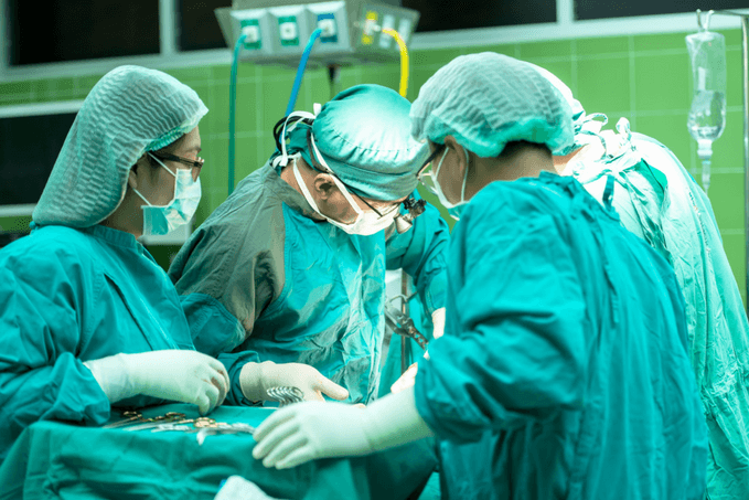 A team of surgeons in scrubs performing an operation in a surgical room.