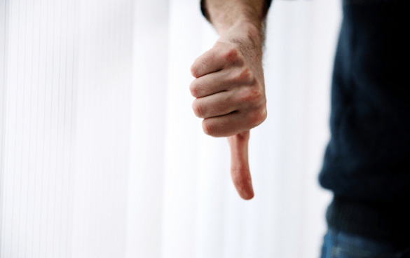 A person's hand with thumb pointing down against a plain white background.