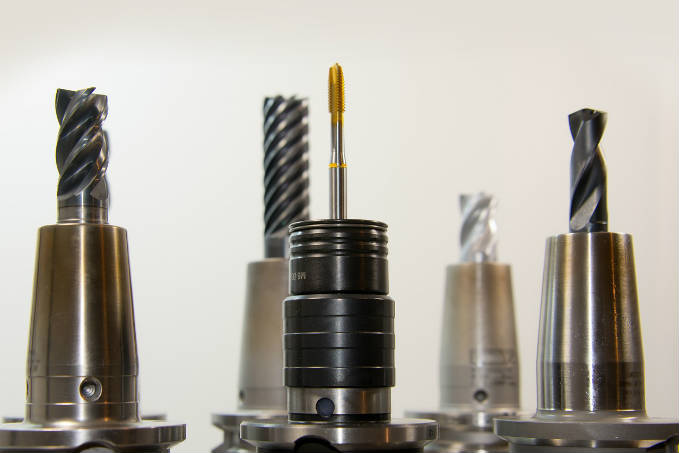 A collection of metal cutting tools for milling or machining, displayed upright with various designs and sizes on a light-colored background.