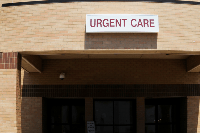 Exterior of an Urgent Care clinic with a sign above the entrance on a brick building facade.