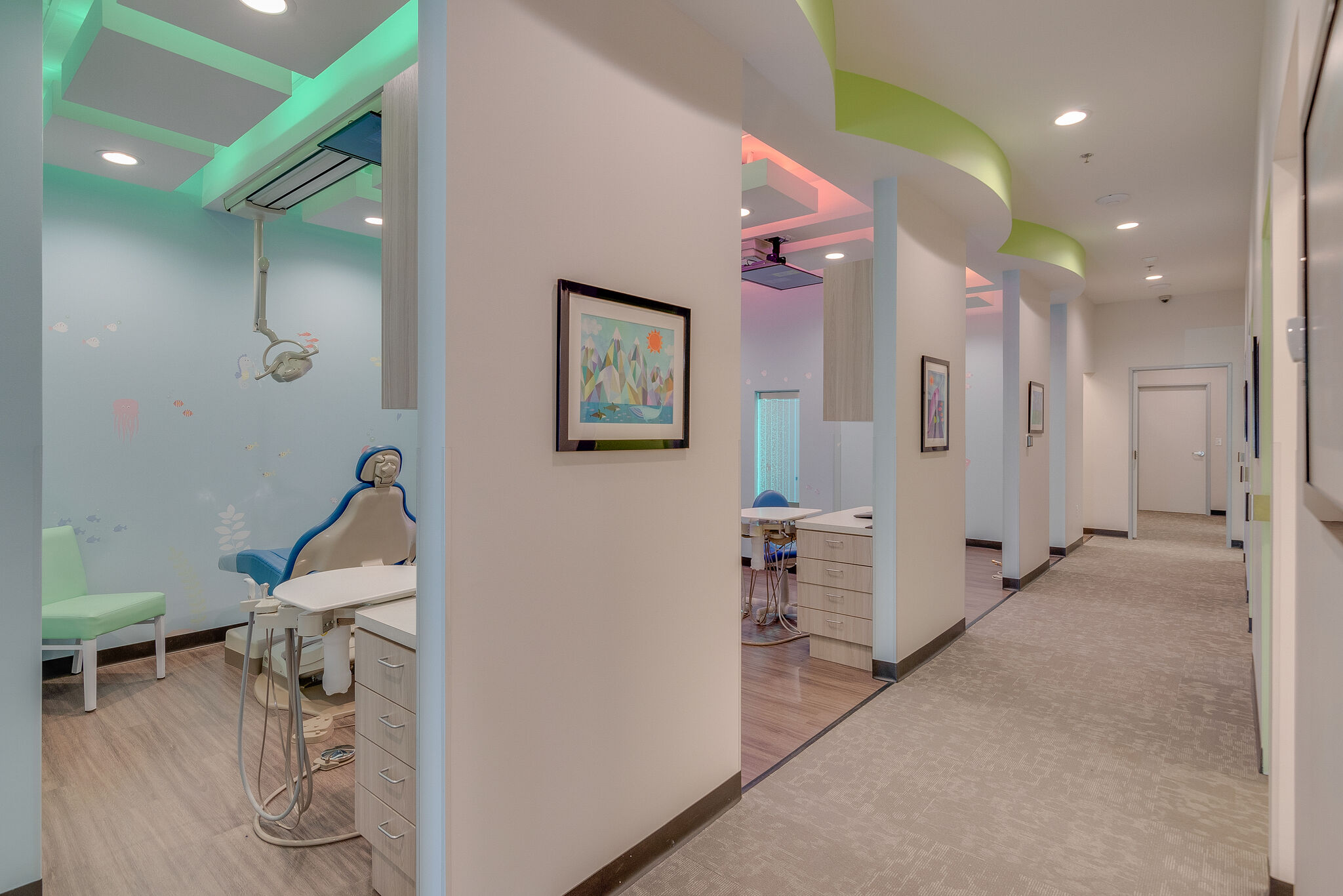 Interior of a pediatric dental clinic with a colorful underwater theme, featuring a dental chair, playful decor, and a corridor leading to additional rooms.