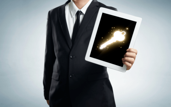 Person in a business suit holding a tablet with a glowing key symbol on the screen.