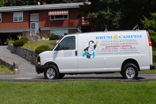 A white service van with 'Bruni & Campisi' branding parked on a residential street, featuring logos and text for plumbing, heating, air conditioning, and emergency services.