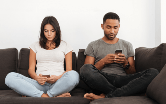 People sitting on a couch scrolling through their phones