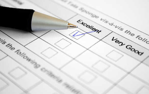 Hand holding a pen marking the 'Excellent' checkbox on a survey form.