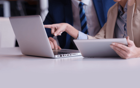 Woman pointing to a laptop while holding a tablet