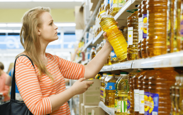 Woman grabbing olive oil from a grocery store shelf