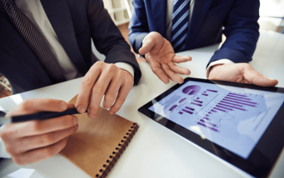 Two men in suits analyzing graph data on a tablet