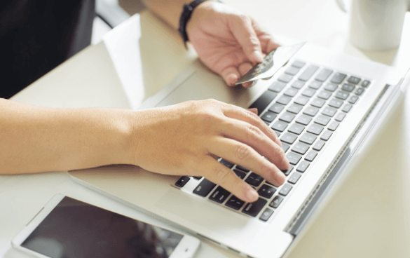 Person shopping online a laptop with their credit card in hand