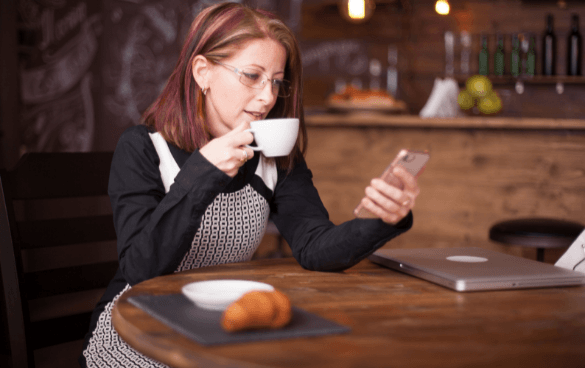 Woman sitting on her phone drinking coffee in a coffee shop