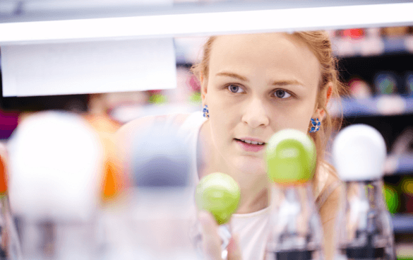 Woman peeking through the product shelves in a grocery store