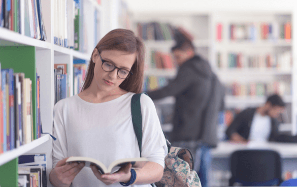 Woman in a library standing and reading a book