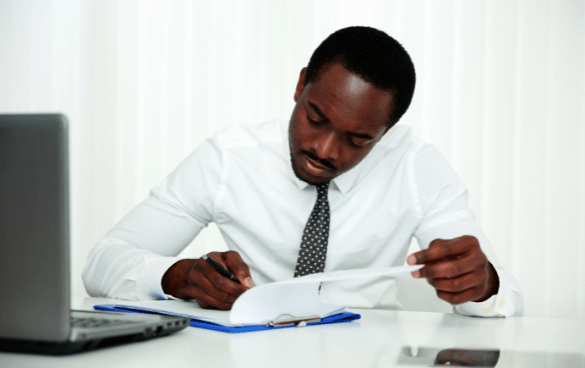 African-American man sitting at a desk, dressed professionally, and writing down information